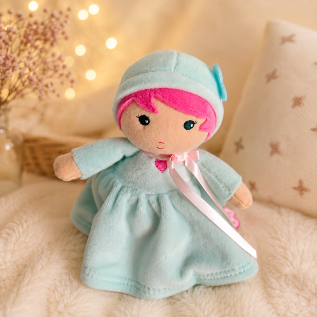 Gros plan sur le visage et la tenue de la poupée Kaloo rose et menthe
