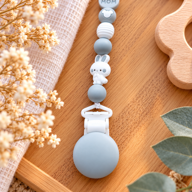Petit lapin et pince de l’attache sucette Détail du petit lapin blanc et de l’attache sucette en silicone gris et blanc