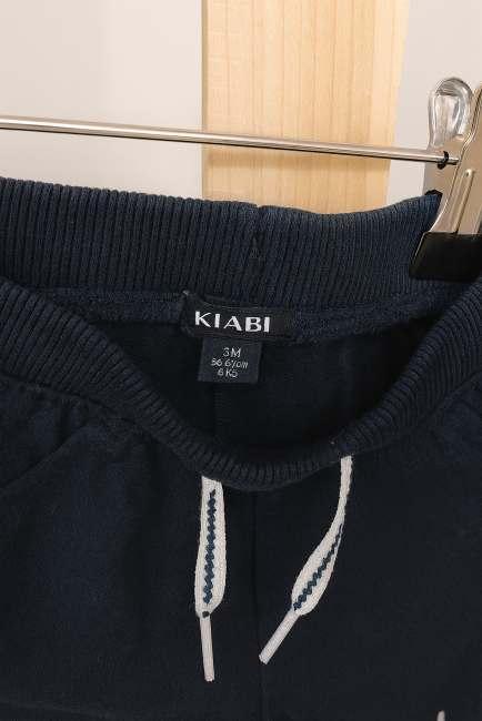 Pantalon bébé bleu marine KIABI taille 3 mois suspendu sur cintre en bois