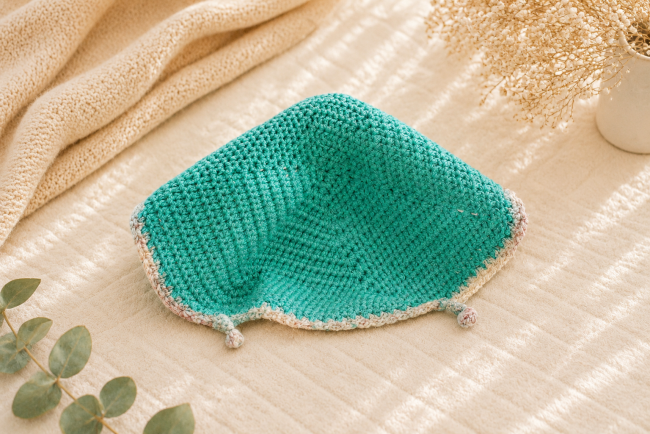 Doudou crochet turquoise artisanal – Accessoire bébé fait main Doudou turquoise au crochet avec bordures pastel dans une ambiance chaleureuse et apaisante