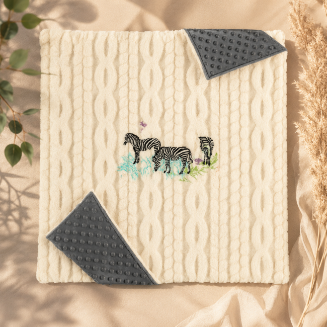Détail brodé de trois zèbres et papillons sur couverture bébé artisanale