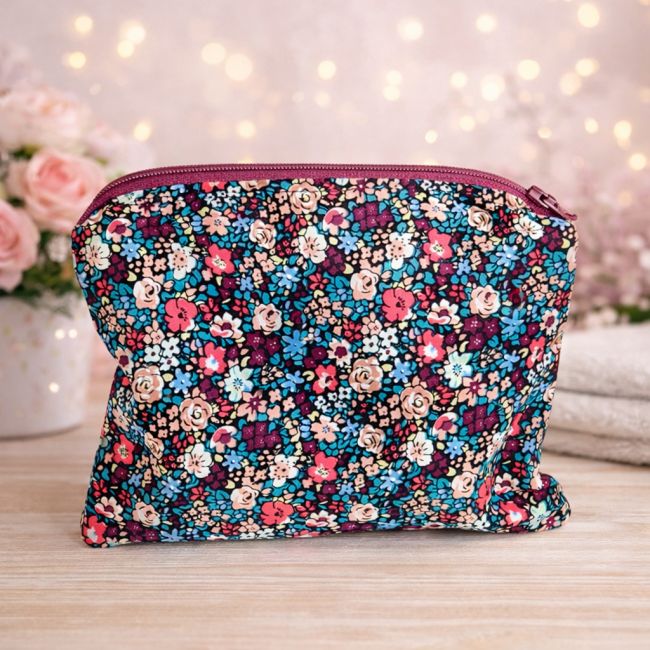 Trousse artisanale fleurie – vue fermé Trousse artisanale fleurie fermée, motif multicolore sur fond sombre, posée dans une ambiance douce et lumineuse.