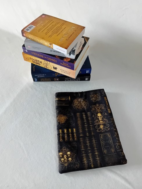 Pochette à livres Bibliothèque des Ombres – Univers Gothique | Les Cabas en folie Pochette à livres Bibliothèque des Ombres 21 x 28 cm en coton imprimé noir avec livres anciens, ornements dorés et crânes – Les Cabas en folie