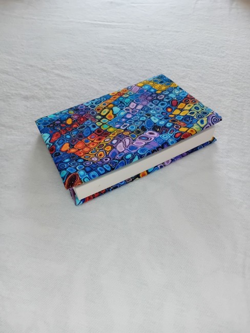 Protège-livre Mosaïque de couleurs inspirée de Klimt | Les Cabas en folie Protège-livre fait main aux motifs colorés inspirés de l'univers décoratif de Klimt, posé sur un tissu mauve.