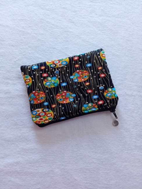 Trousse multi-usage au motif graphique coloré sur fond noir avec fermeture zip et breloque