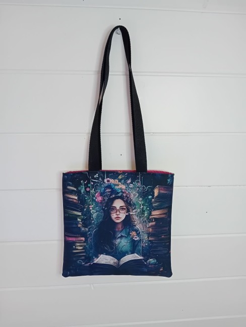 Tote bag La lectrice enchantée avec jeune lectrice entourée de livres, face imprimée et anses noires – Les Cabas en folie 