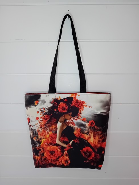 Cabas « Éclat floral » – Sac cabas artisanal | Les Cabas en folie Cabas artisanal « Éclat floral » avec femme au chapeau entourée de fleurs rouges et orangées
