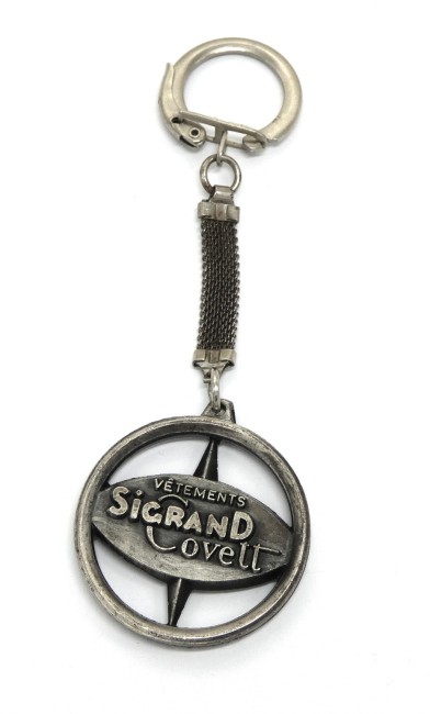 Ancien porte clé publicitaire en  métal rose des vents vêtements Sigrand