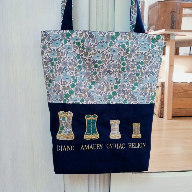 Vue de face du totebag cabas personnalisé avec tissu fleuri, anses bleu marine et bottes brodées