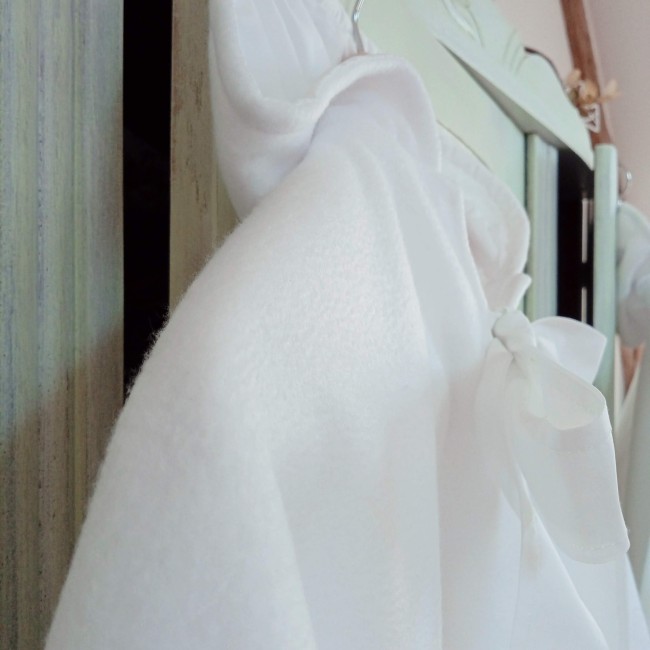 Capuche et ruban de fermeture d'une cape de baptême blanche