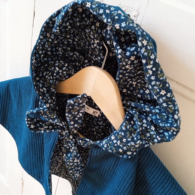 une jolie cape en velours côtelé de couleur paon doublée d'un superbe tissu fleuri