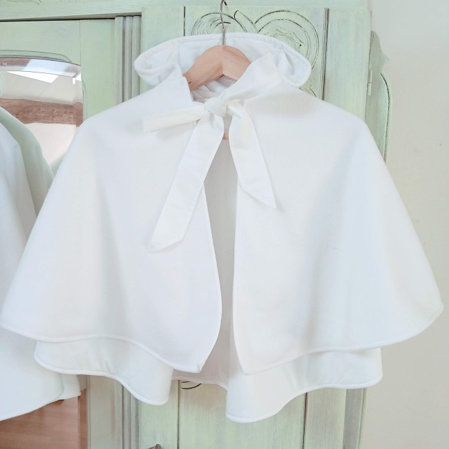 Cape de baptême blanche chaude avec capuche avec ruban présentée dans l'atelier