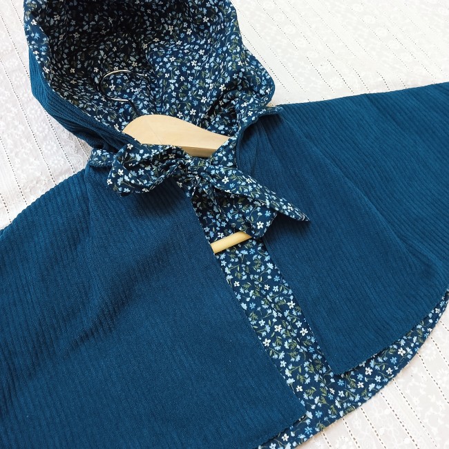 une jolie cape en velours côtelé de couleur paon doublée d'un superbe tissu fleuri