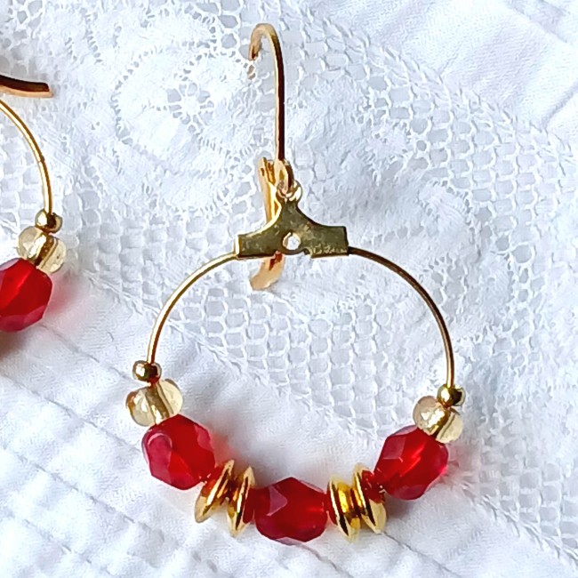 Zoom sur la boucle d'oreille perles de cristal rouge et intercalaires métal doré