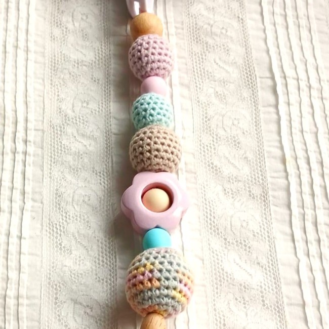 une petite perle est placée dans la fleur, pour accentuer la motricité fine de bébé