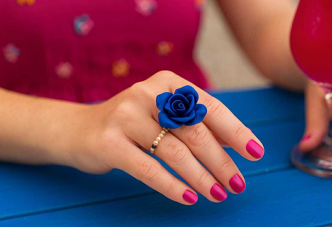 Bague fleur bleue Caprissa en pâte polymère, portée avec élégance lors d’un moment lifestyle chic et coloré.