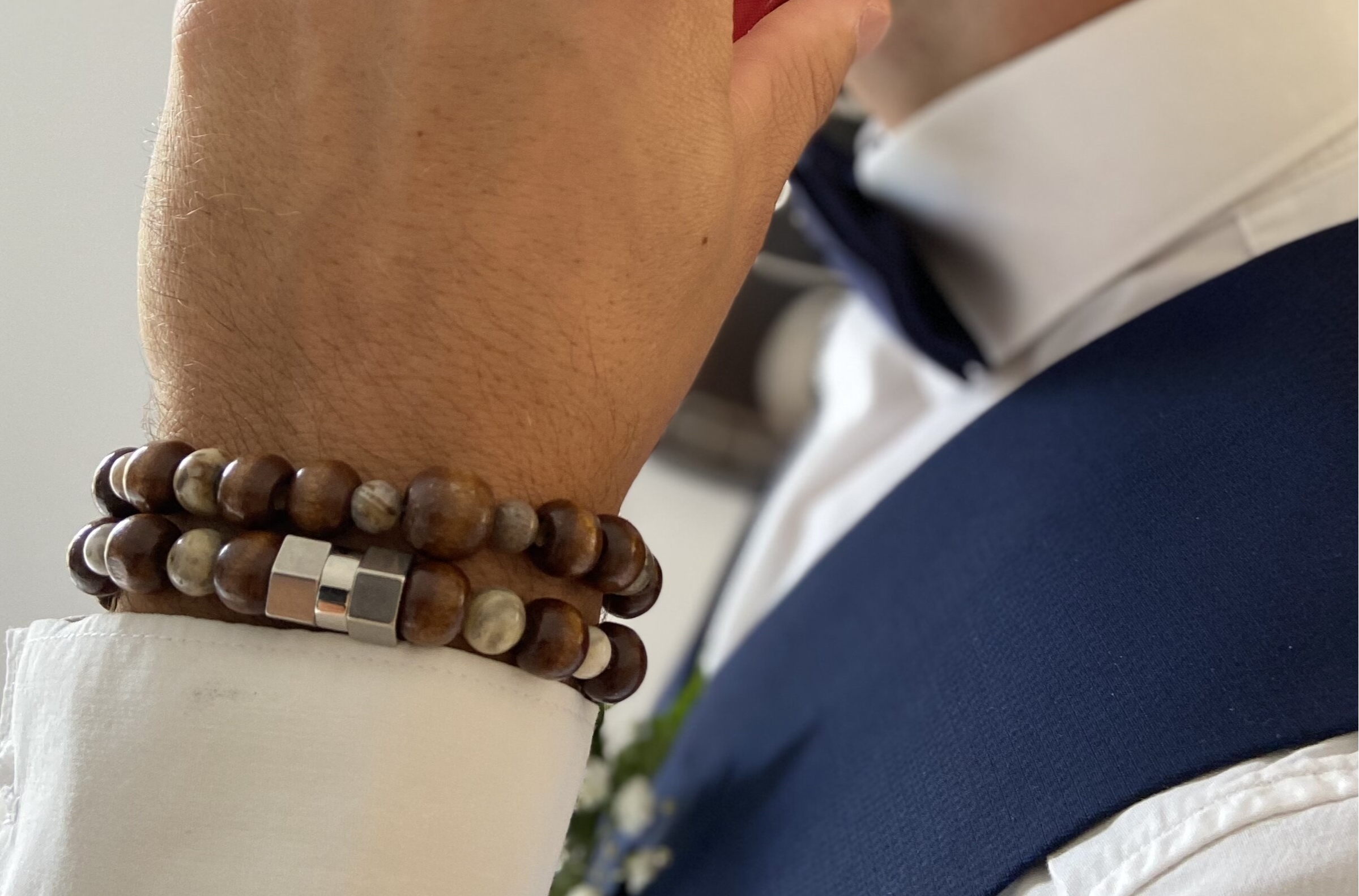 Bracelet homme en perles naturelles marron et beige porté avec un costume bleu – bijou masculin élégant Caprissa Créations
