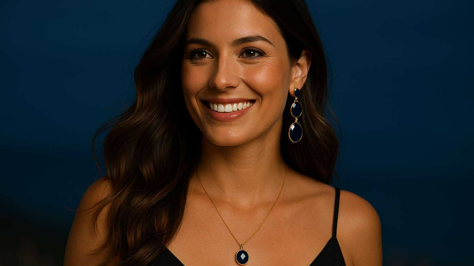 emme souriante portant des bijoux dorés et bleu nuit Caprissa Créations, ambiance élégante et lumineuse inspirée de la nuit