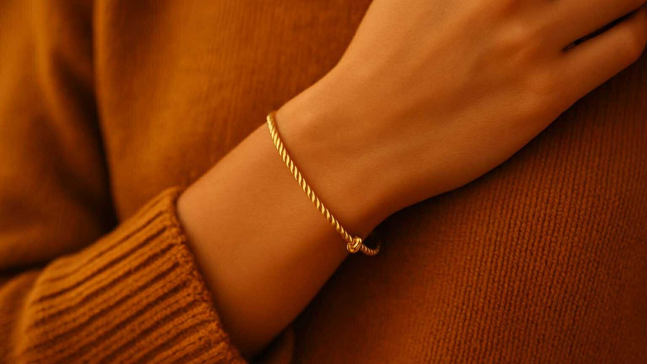 Bracelet doré torsadé porté sur un pull ocre, création élégante Caprissa Créations