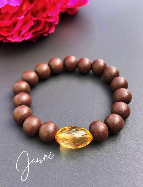 Bracelet fantaisie composé de perles de bois d'un brun mat et d'une perle de verre ovale à la couleur éclatante jaune pour un contraste à la fois chaleureux et lumineux.