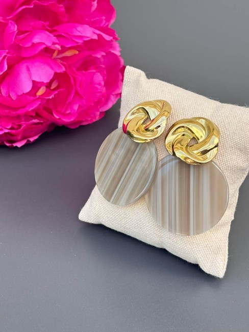 Boucles d'oreille fantaisie composé d'un pendentif en résine rond de couleur taupe et réhaussé d'un apprêt en forme de noeud en acier inoxydable doré pour un style rétro chic