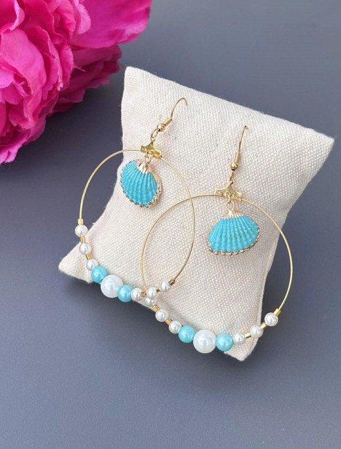 Boucle d'oreille fantaisie composé de perles d'eau douce blanches montées sur la créole et d'un coquillage au centre