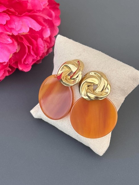 Boucles d'oreille fantaisie composé d'un pendentif en résine rond de couleur marron ambré et réhaussé d'un apprêt en forme de noeud en acier inoxydable doré pour un style rétro chic
