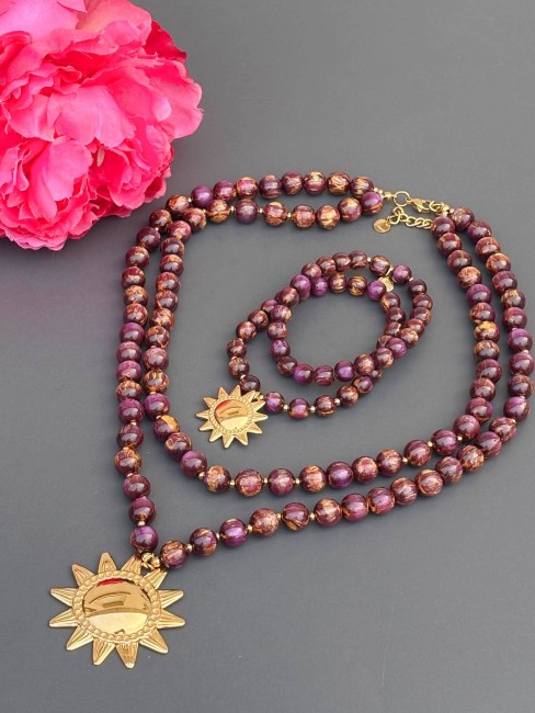 Collier et bracelet double range fantaisie composé de perles en résines aux nuances violettes, marronées et jaunes réhaussé par un pendentif soleil en acier inoxydable doré pour un style féminin chic et solaire