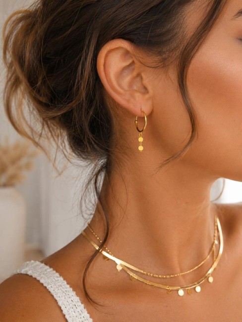 Boucles d'oreille créoles fantaisies réhaussées par des pampilles en acier inoxydable doré pour un look bohème chic