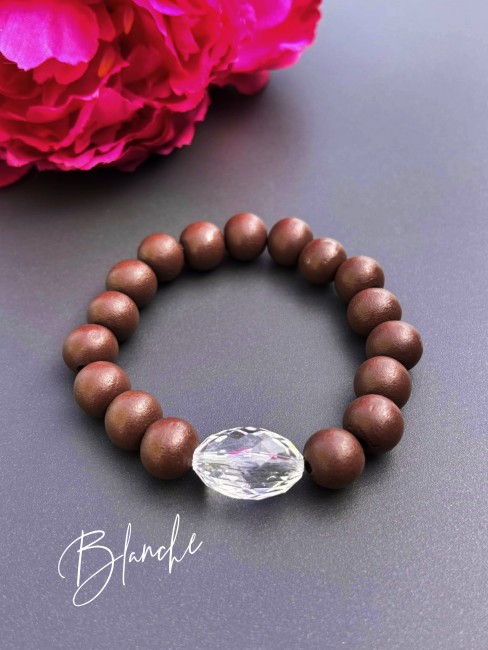 Bracelet fantaisie composé de perles de bois d'un brun mat et d'une perle de verre ovale à la couleur éclatante blanche pour un contraste à la fois chaleureux et lumineux.