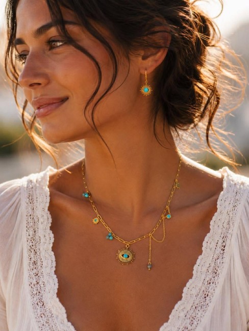 ATHENA - Collier oeil de protection en acier inoxydable doré et perle naturelle apatite bleu Collier oeil porte bonheur en acier inoxydable composé de charms de perles naturelle en apatite bleu ainsi que des zirconium, pensé pour celles qui aiment porter un bijou aussi beau que symbolique