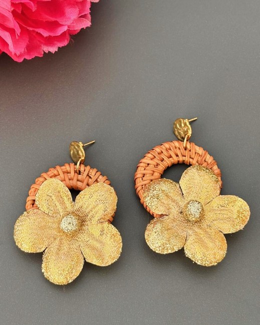 Boucles d'oreilles fantaisie composées d'une base en rotin naturel agrémenté d'une délicate fleur dorée et  d'un apprêt en acier inoxydable argenté qui apportera une dimension supplémentaire au design du bijou en ajoutant u