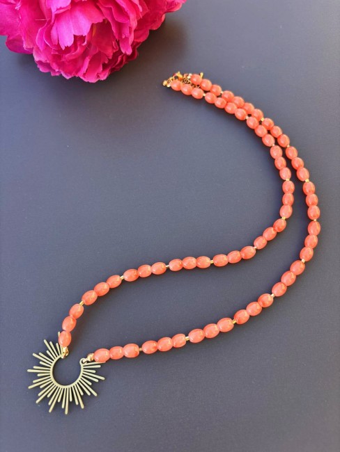Colliert fantaisie composé de perles naturelle de couleurs corail pour un effet bohème chic et raffiné et réhaussé par un pendentif en forme de soleil en acier inoxydable doré