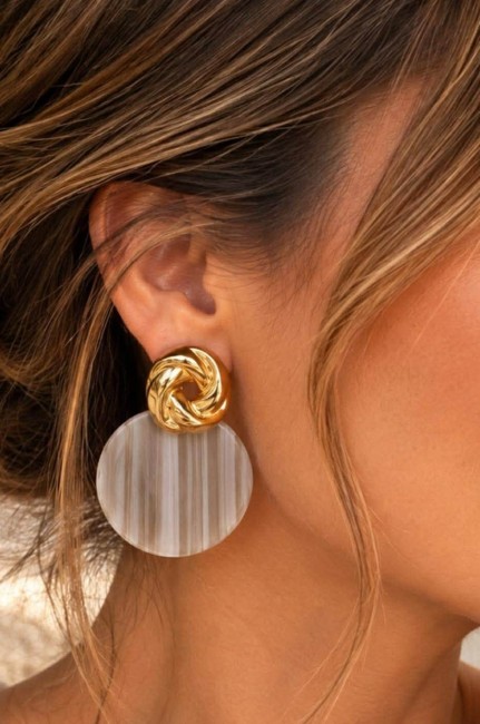 Boucles d'oreille fantaisie composé d'un pendentif en résine rond de couleur taupe et réhaussé d'un apprêt en forme de noeud en acier inoxydable doré pour un style rétro chic