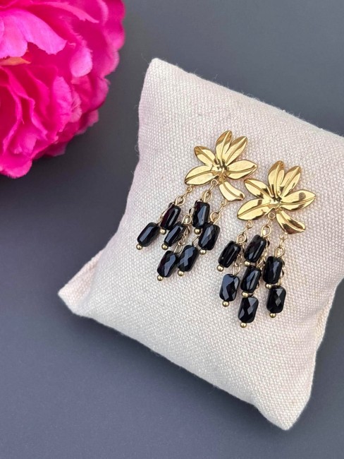 Boucles d'oreilles fantaisie composées d'une fleur en acier inoxydables et de perles naturelles pendantes en agate noir, ce qui donne un effet bohème chic et solaire