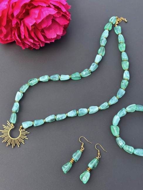 Ensemble composé d'un collier, de boucles d'oreilles et d'un bracelet de perles naturelles de couleurs vert d'eau pour un style hypnotisant coloré et bohème chic; à noter que le collier est réhaussé d'un pendentif en acier inoxydable en forme de soleil