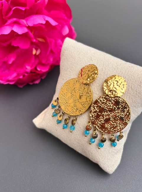 MILOS - Boucles d'oreilles martelées et perles naturelles en apatite bleu Inspirées des paysages lumineux de la Méditerranée, les boucles MILOS séduisent par leurs disques martelés aux reflets dorés et leurs délicates perles naturelles facettées en apatite bleu