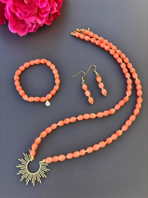 Ensemble composé d'un collier, de boucles d'oreilles et d'un bracelet de perles naturelles de couleurs corail pour un style hypnotisant coloré et bohème chic; à noter que le collier est réhaussé d'un pendentif en acier inoxydable en forme de soleil