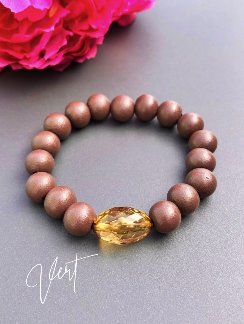 Bracelet fantaisie composé de perles de bois d'un brun mat et d'une perle de verre ovale à la couleur éclatante verte pour un contraste à la fois chaleureux et lumineux.