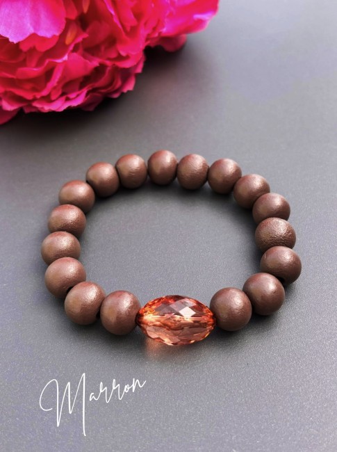 Bracelet fantaisie composé de perles de bois d'un brun mat et d'une perle de verre ovale à la couleur éclatante marron pour un contraste à la fois chaleureux et lumineux.
