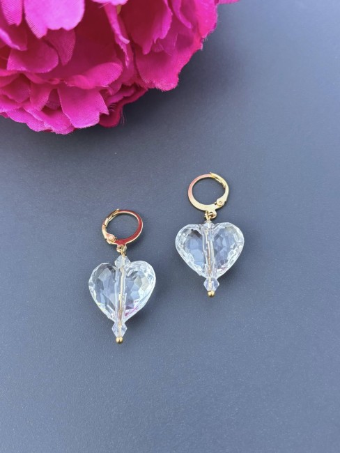 Boucles d'oreille fantaisie composé d'une perles de verre blanches transparente en forme de coeur réhaussé par un apprêt dormeuse en acier inoxydable doré