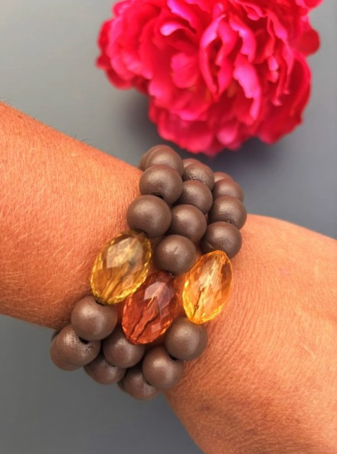Bracelet fantaisie composé de perles de bois d'un brun mat et d'une perle de verre ovale aux couleur éclatante  pour un contraste à la fois chaleureux et lumineux.
