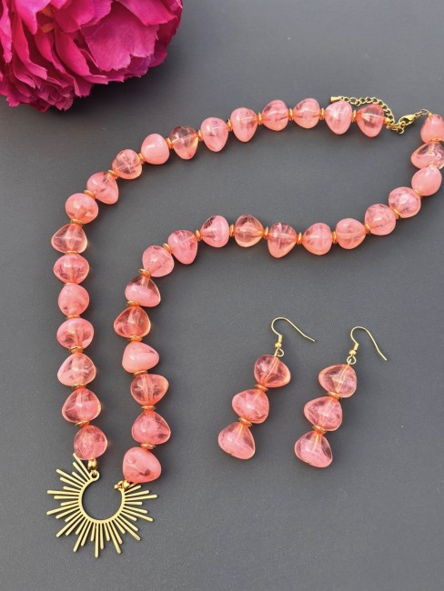 Ensemble composé d'un collier et de boucles d'oreilles de perles naturelles de couleurs corail pour un style hypnotisant coloré et bohème chic; à noter que le collier est réhaussé d'un pendentif en acier inoxydable en forme de soleil