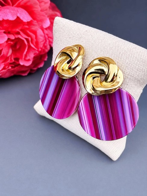 Boucles d'oreille fantaisie composé d'un pendentif en résine rond de couleur violet rose et réhaussé d'un apprêt en forme de noeud en acier inoxydable doré pour un style rétro chic