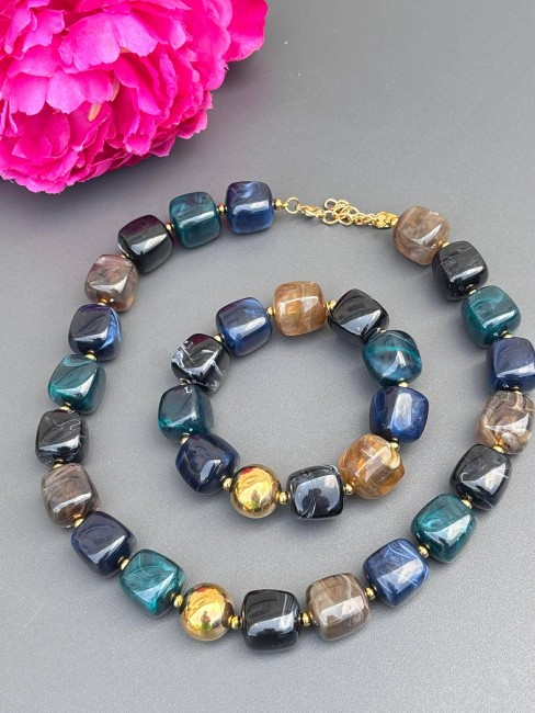 BYZANCE - Parure Collier et bracelet aux perles de résines aux teintes bleutées marronées et doré Parure BYZANCE composée d'un Collier et d'un bracelet aux perles de résines aux teintes bleutées marronées et doré pour un style bohème choc oriental nomade