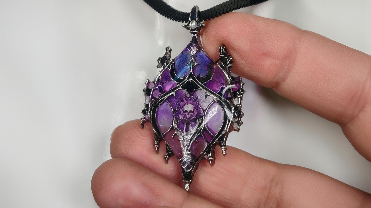 Pendentif gothique translucide Noctilith fait main, collection Les Sœurs de la Nuit, présenté entre les doigts sur fond blanc