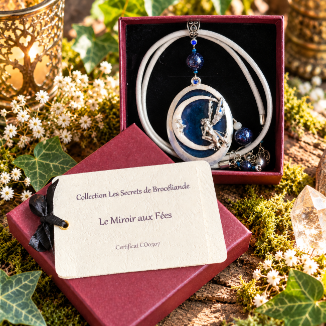 Collier artisanal Le Miroir aux Fées, médaillon bleu et argent représentant une fée sur un croissant de lune, présenté dans son écrin bordeaux avec son certificat d’identification.