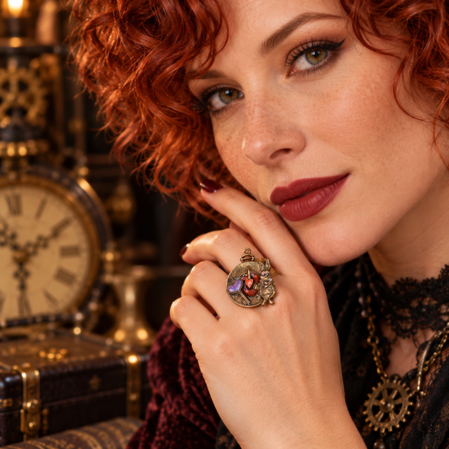 Mise en scène de la bague Le Retard du Lapin Blanc portée par une femme, au cœur d’un univers steampunk chaleureux inspiré du Pays des Merveilles