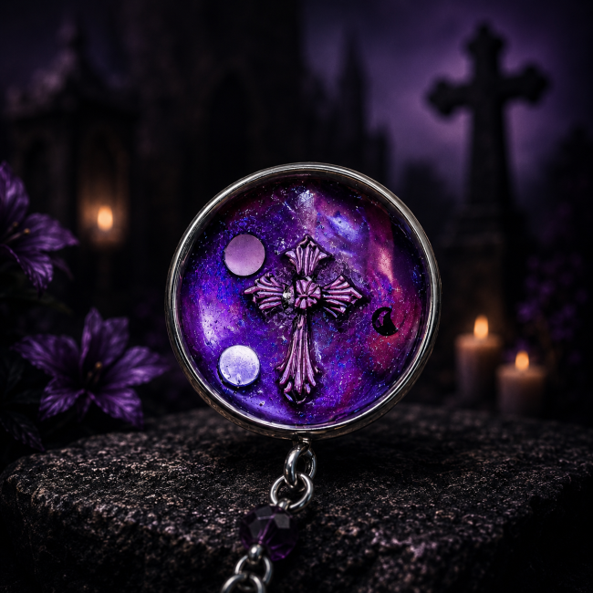 Clou d’Oreilles Noctilith Croix Violette | Les Sœurs de la Nuit Zoom sur un clou d’oreilles Noctilith orné d’une croix gothique violette, issu de la collection Les Sœurs de la Nuit, dans un décor de vieux cimetière gothique éclairé à la bougie.