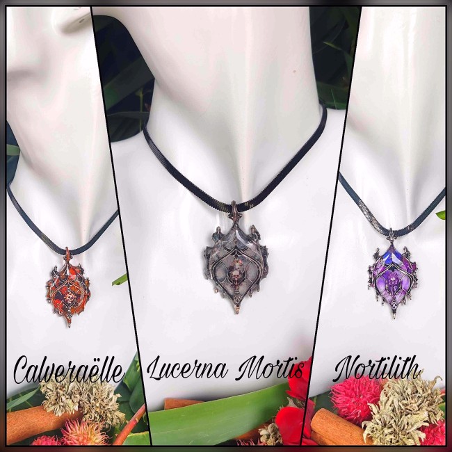 Trois colliers gothiques Les Sœurs de la Nuit présentés sur buste blanc, pendentifs vitrail émaillés et chaînes serpentines noires